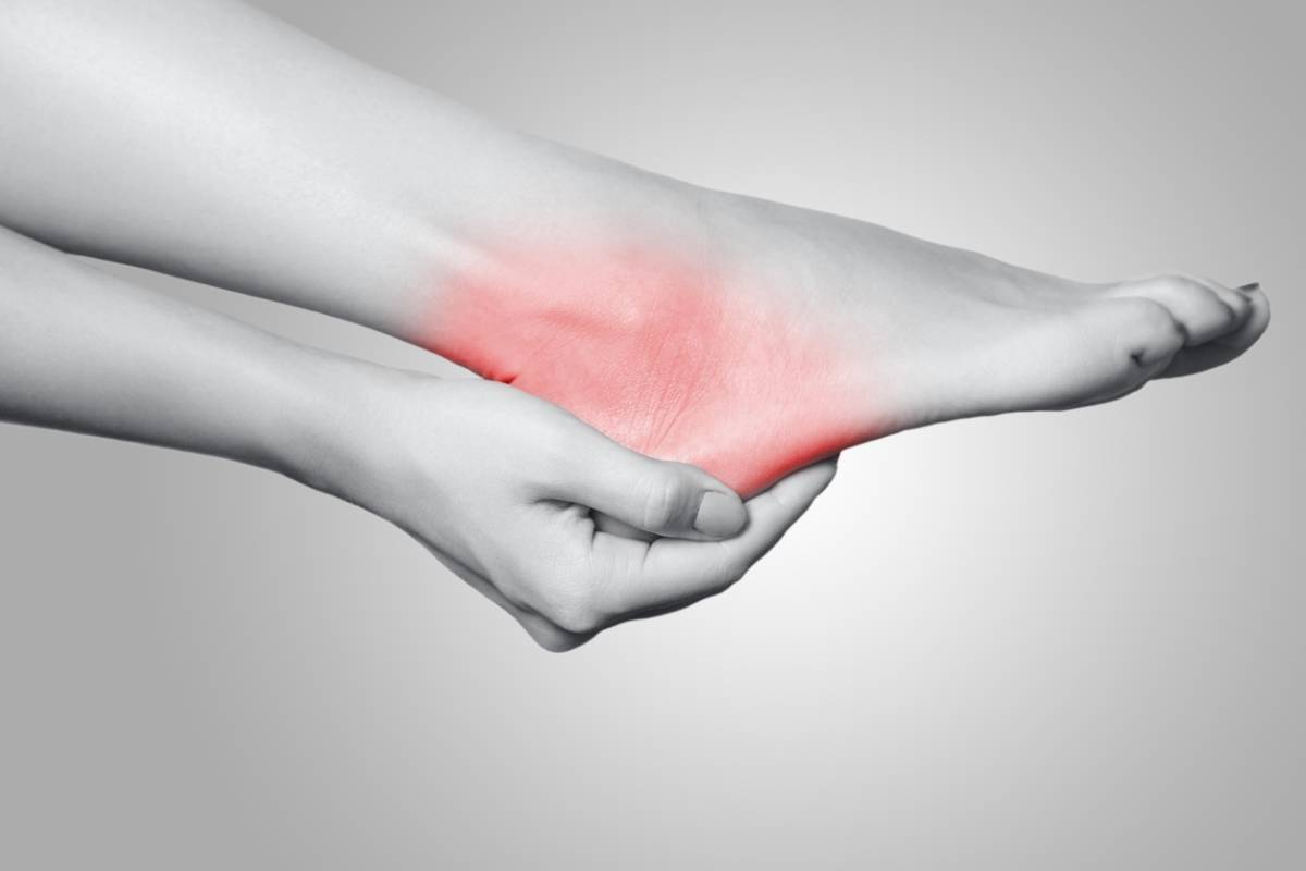 Closeup view of a young woman with pain on leg on gray background.